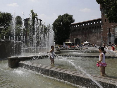 Hai bé gái chơi đùa với nước tránh nóng ở Milan, Italy.